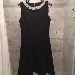 Black sleeveless pearl boat neck dress